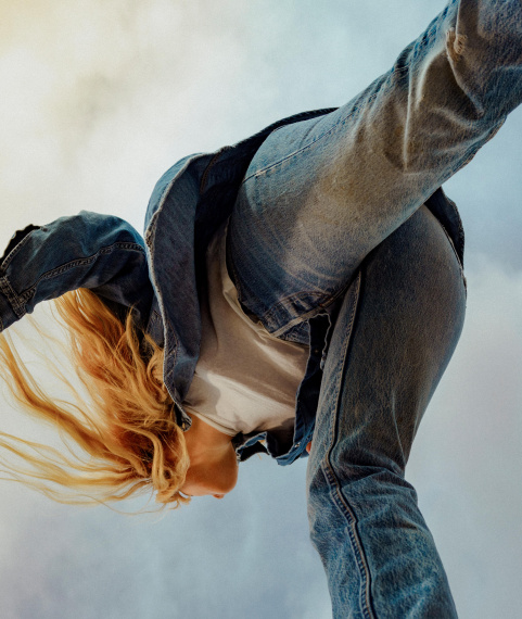 Girl wearing levi's 501 denim made with circulose walking in dusky blue sky background